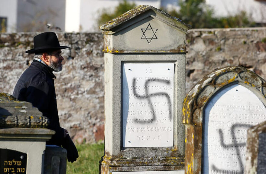 A man walks past graves desecrated with swastikas at the Jewish cemetery in Westhoffen, near Strasbourg, France, December 4, 2019.(photo credit: Arnd Wiegmann/Reuters)